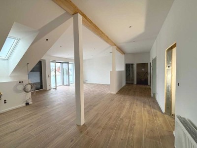 Moderne DG-Wohnung, Wohnzimmer mit offener Küche und großem Balkon.