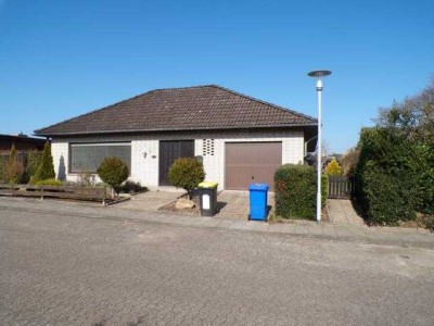 Walmdachbungalow mit innenliegender Garage und Holzgartenhaus